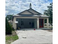 View of charming beige single-story home with a red front door and a two-car garage with a concrete driveway at 3413 N 72Nd St, Tampa, FL 33619