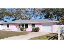 Charming pink single-story home with a well-maintained front yard and attached garage at 675 Marjon Ave, Dunedin, FL 34698