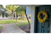 View of the front door with yellow wreath, sidewalk, lawn and palms at 718 Lyndhurst St # 904, Dunedin, FL 34698