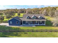 Charming blue home featuring a welcoming front porch, well-manicured lawn, and a classic fence enhancing its curb appeal at 10946 Gun Dog Way, Lithia, FL 33547