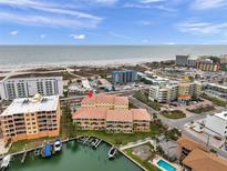 Breathtaking aerial view of a yellow condo building situated on a waterfront with private boat docks and beach access at 11555 Gulf Blvd Blvd # 115, Treasure Island, FL 33706