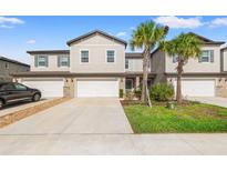 Townhome with a two-car garage, concrete driveway, stone accents and landscaping with palm trees at 21181 Threadfin Way, Land O Lakes, FL 34638