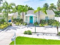 Charming home featuring a bright blue front door and lush tropical landscaping at 744 Bay Esplanade, Clearwater Beach, FL 33767