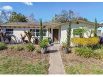 Charming home featuring meticulously landscaped front yard with mature trees and vibrant flower beds at 921 39Th Ne Ave, St Petersburg, FL 33703