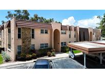 Condo building with tan stucco, decorative stone accents, and covered parking in front at 110 Aspen Cir, Seminole, FL 33777