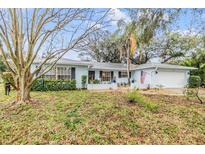 Charming single-story home with a manicured lawn and mature trees, showcasing its inviting curb appeal at 1421 Monte Carlo Dr, Clearwater, FL 33764