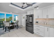 Bright kitchen with sleek black refrigerator, white cabinets, and breakfast nook with water views at 150 Belleview Blvd # 307, Belleair, FL 33756