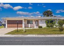 Charming single-story home with a well-manicured lawn, a brown garage door, and decorative front features at 1517 Danbury Dr, Sun City Center, FL 33573