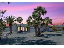 Charming single-story home featuring lush landscaping, a circular driveway and beautiful curb appeal at sunset at 2504 Bayshore Dr, Belleair Beach, FL 33786