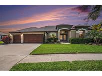 Beautiful single Gathering home with well-manicured lawn and a three car garage at sunset at 350 Cockle Shell Loop, Apollo Beach, FL 33572