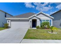Charming single-story home with a two-car garage, complemented by well-maintained landscaping and a blue sky at 38255 Sonnet Landing Ave, Zephyrhills, FL 33540