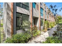 Modern townhome featuring a stylish facade with large windows and lush landscaping at 4156 Gauge Line Loop, Tampa, FL 33624