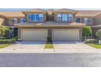 Attractive townhome featuring tan stucco and a two-car garage with tiled roof and well-manicured landscaping at 4739 Silverking Way, Palm Harbor, FL 34684