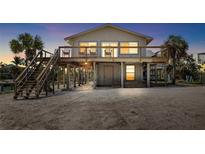 Beautiful elevated coastal home with a spacious deck, stairs, and beach access at sunset at 9696 Little Gasparilla Isand, Placida, FL 33946