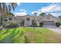 Charming single-story home features a well-manicured lawn, lush landscaping, and a two-car garage at 14472 Linden Dr, Spring Hill, FL 34609