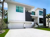 Contemporary home with white exterior, dark accents, large windows, and a three-car garage at 4816 W San Jose St, Tampa, FL 33629