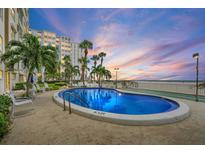 Beautiful community pool near beach, featuring lush tropical landscaping and lounge chairs at 5000 Gulf Blvd # 304, St Pete Beach, FL 33706