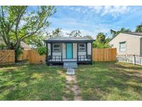 Charming home featuring a cozy front porch and a bright, inviting blue front door at 8308 N Mulberry St, Tampa, FL 33604