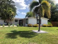 Charming single-story home featuring a well-manicured lawn and lush tropical landscaping in a sunny neighborhood at 907 Fruitland Ave, Bradenton, FL 34207