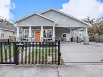 Charming single-story home featuring a welcoming front porch, orange door, well-manicured lawn, and a gated entrance at 1003 W Reynolds St, Plant City, FL 33563