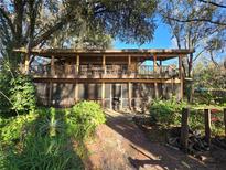 Charming two-story home with a wooden exterior and front porch, surrounded by lush landscaping and mature trees at 18886 Crescent Rd, Odessa, FL 33556