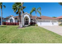 Charming single-story home featuring a well-manicured lawn, arched entryway, and a convenient three-car garage at 6014 Mariners Watch Dr, Tampa, FL 33615