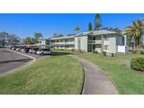 Two-story building with well-maintained lawn, mature trees, covered parking, and convenient walkway access at 128 Nancy Dr # 128, Oldsmar, FL 34677