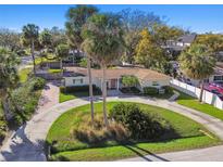 Charming home featuring lush landscaping, a circular driveway and mature palm trees at 1905 S Hesperides St, Tampa, FL 33629