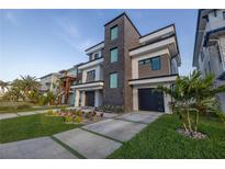 Modern three-story home with a sleek gray and white exterior and well manicured landscaping at 201 Punta Vista Dr, St Pete Beach, FL 33706