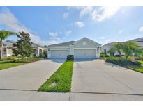 Charming home exterior featuring a spacious two-car garage and well-manicured landscaping with green grass and a blue sky at 4524 Deep Creek Ter, Parrish, FL 34219