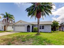 Charming single-story home with a well-maintained lawn, mature palm trees, and attached two car garage at 7034 Southwind Dr, Hudson, FL 34667