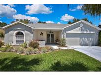 Charming single-story home boasts a manicured lawn, a covered front porch, and an attached two-car garage at 8045 Sugarbush Dr, Spring Hill, FL 34606