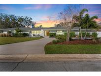 Charming home with a manicured front lawn, beautiful landscaping, and a long driveway leading up to the house at 1664 Sharon Way, Clearwater, FL 33764