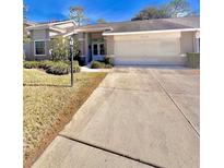 Charming home with a manicured lawn, inviting entrance, and two-car garage on a sunny day at 2439 Hidden Trail Dr, Spring Hill, FL 34606