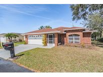 Charming single-story brick home featuring a well-manicured lawn and attached two-car garage at 29443 Zeller Ave, San Antonio, FL 33576