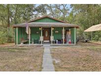 Charming green home with a cozy front porch and inviting swing at 303 Grand Ave, Brooksville, FL 34604