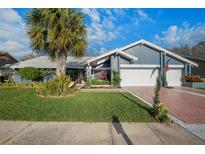 Charming single-story home featuring a well-manicured lawn, a two-car garage, and an American flag at 3275 Valemoor Dr, Palm Harbor, FL 34685