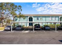 Exterior view of condo building with covered parking featuring vibrant blue accents and well-maintained landscaping at 11407 3Rd N St # 1, St Petersburg, FL 33716
