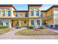 Inviting yellow townhouse with manicured landscaping, brick walkway, and covered porch at 3870 Island Way, St Petersburg, FL 33705