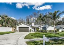 Charming one-story home featuring a well-manicured lawn, mature trees, and a two-car garage at 4308 Grainary Ave, Tampa, FL 33624