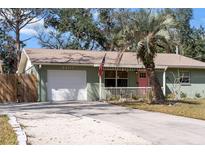 Charming single-story home featuring a light green exterior, well-manicured lawn and a bright pink front door at 4407 Parnell Dr, Sarasota, FL 34232
