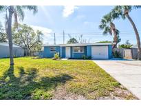 Charming single-story home with blue exterior, manicured lawn, driveway, and lush palm trees at 5600 Bay Ne St, St Petersburg, FL 33703