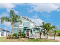 Inviting two-story home showcasing lush landscaping with vibrant palms against a blue sky backdrop at 10639 Carloway Hills Dr, Wimauma, FL 33598