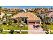 Stunning aerial view of a home with lush landscaping, a three-car garage and a pond at 1335 Jumana Loop, Apollo Beach, FL 33572