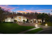 Picturesque view of a Mediterranean-style home at dusk, showing the red tile roof and lush landscaping at 5204 Avenue La Crosse, Lutz, FL 33558