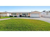 Charming one-story home featuring lush green lawn and a large driveway leading to an attached two-car garage at 6648 12Th N Ave, St Petersburg, FL 33710