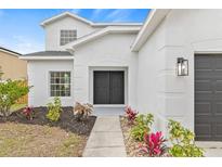 Charming home featuring a black front door, well-maintained landscaping, and a light-colored stucco exterior at 7604 Dragon Fly Loop, Gibsonton, FL 33534