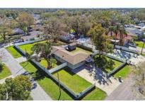 Charming single-story home featuring a spacious lawn, long driveway, and a well-manicured landscape surrounded by a white fence at 8025 N Gomez Ave, Tampa, FL 33614