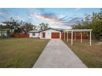 Charming single-story home with a well-manicured lawn and a long concrete driveway leading to a wooden garage at 208 Palmetto W Rd, Nokomis, FL 34275