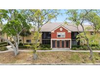 Well-maintained condo building featuring a red accent wall and lush, mature trees in a desirable location at 5618 Baywater Dr # 5618, Tampa, FL 33615